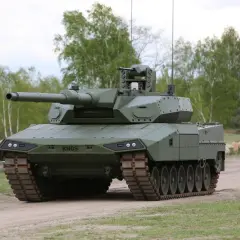 Ein moderner Kampfpanzer, der zeigt, wie gut der Leopard 2 ist. Er steht auf einem Feldweg, umgeben von Bäumen.