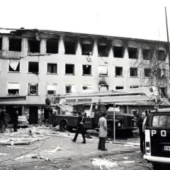 Nach der Operation Nimrod: ausgebranntes Gebäude, Feuerwehr und Polizei im Einsatz. Trümmer bedecken den Boden.