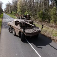 Ein moderner Jaguar-Panzer, ein stolzes Stück Militärtechnik aus Frankreich, fährt auf einer einsamen Straße durch bewaldetes Gebiet.