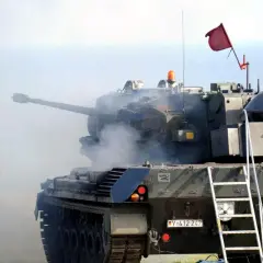 Ein Flakpanzer 1 feuert, Patronenhülsen fliegen durch die Luft. Rauch steigt aus dem Turm auf.