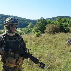 Soldat der Bundeswehr mit Tarnmuster und Gewehr im Feld. Die 5 Streifen auf seiner Ausrüstung sind kaum zu erkennen.