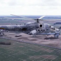 Ein Mi-24 Hind Hubschrauber der Bundeswehr fliegt über ein ländliches Gebiet.