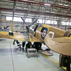 Flugzeugmuseum Usedom: Techniker arbeiten an einem historischen Jagdflugzeug in einer Werkstatthalle.
