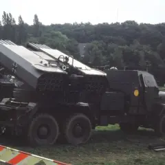 Lars Panzer, ein Raketenwerfer auf einem LKW, steht im Gras. Im Hintergrund ein Panzer.