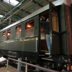 Ein Mann arbeitet an einem historischen Zugwaggon, der an Hitlers Panzerzug erinnert.