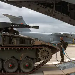 Ein Soldat sichert einen Panzer, der für den Transport in ein großes Flugzeug vorbereitet wird.