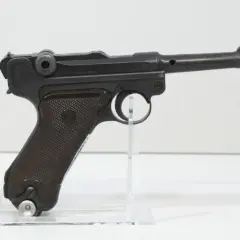 Eine schwarze Luger P08 Wehrmacht Pistole mit braunen Griffschalen, auf einem transparenten Ständer.