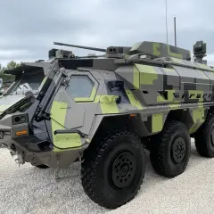 Ein gepanzertes Fahrzeug mit Tarnmuster, das als Fennek-Nachfolger präsentiert wird. Es verfügt über eine Waffenstation und mehrere Sensoren.