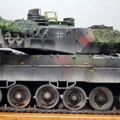 Detailaufnahme eines deutschen Panzers im Tarnmuster mit Tarnnetz. Das Modell zeigt die charakteristischen Räder und Ketten.