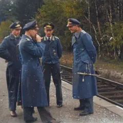 Vier Männer in blauen Uniformen, einige mit Portepee, stehen am Bahnsteig.
