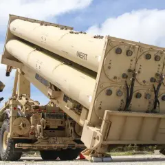 Soldat lädt Raketen für das THAAD-System. Große, beige Raketen sind auf einem LKW montiert, bereit für den Einsatz.
