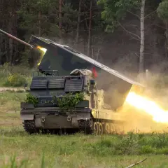 Ein Raketenwerfer auf Panzerbasis feuert eine Rakete ab, begleitet von hellem Feuer und Rauch.