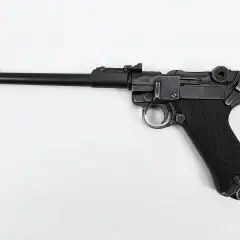 Eine schwarze Luger Pistole mit nummeriertem Schlitten (938) und geriffeltem Griff liegt auf weißem Grund.