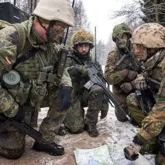 Soldaten der Bundeswehr im Wald, ein Leutnant deutet auf eine Karte.