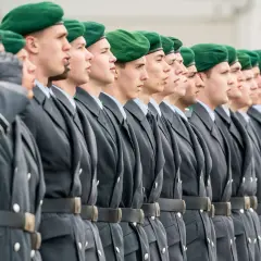Soldaten der Bundeswehr in grünen Baretts und grauen Uniformen stehen stramm. Sie repräsentieren den niedrigsten Rang, bereit für ihren Dienst.