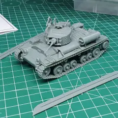 Ein grauer Modellbausatz eines Valentine Panzers liegt auf einer grünen Schneidematte. Zwei separate Panzerplatten liegen daneben.