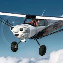 Zwei Piloten fliegen in einer CubCrafters X-Cub über den Wolken.
