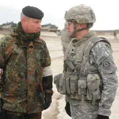 Zwei Soldaten im Gespräch, einer mit deutschem Tarnmuster und schwarzem Barett, der andere in US-Uniform. Der deutsche Soldat trägt den oberstleutnant dienstgrad.