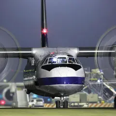 Ein Propellerflugzeug vom Typ Antonow An-26b steht im Scheinwerferlicht auf dem Rollfeld.