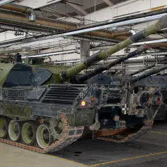 Mehrere Leopard 1 Panzer stehen in einer Halle. Ihre Kanonen ragen nach oben.