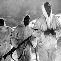 Drei Soldaten der Wehrmacht in Wintertarnung auf dem Elbrus, einer mit Fernglas, ein anderer mit Gewehr.