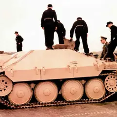 Männer in Uniformen stehen auf und neben einem hellbraunen Opel Hetzer Jagdpanzer.