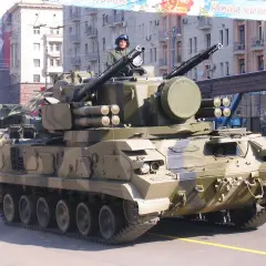 Ein 2K22 Tunguska Flugabwehrpanzer fährt in einer Parade. Der Soldat im Turm trägt einen Helm und eine Uniform.