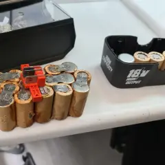 Ein defekter NiCd Akku, bereit für das Nicd Akku wiederbeleben. Daneben ein 18V Akku-Gehäuse.