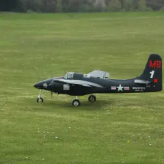 Ein schwarzes Modellflugzeug, ein f7f Tigercat, steht auf einem grünen Feld.