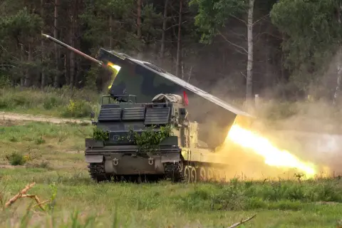 Ein Raketenwerfer auf Panzerbasis feuert eine Rakete ab, begleitet von hellem Feuer und Rauch.