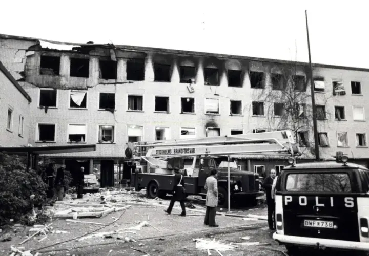 Nach der Operation Nimrod: ausgebranntes Gebäude, Feuerwehr und Polizei im Einsatz. Trümmer bedecken den Boden.