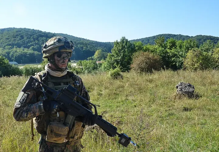 Soldat der Bundeswehr mit Tarnmuster und Gewehr im Feld. Die 5 Streifen auf seiner Ausrüstung sind kaum zu erkennen.