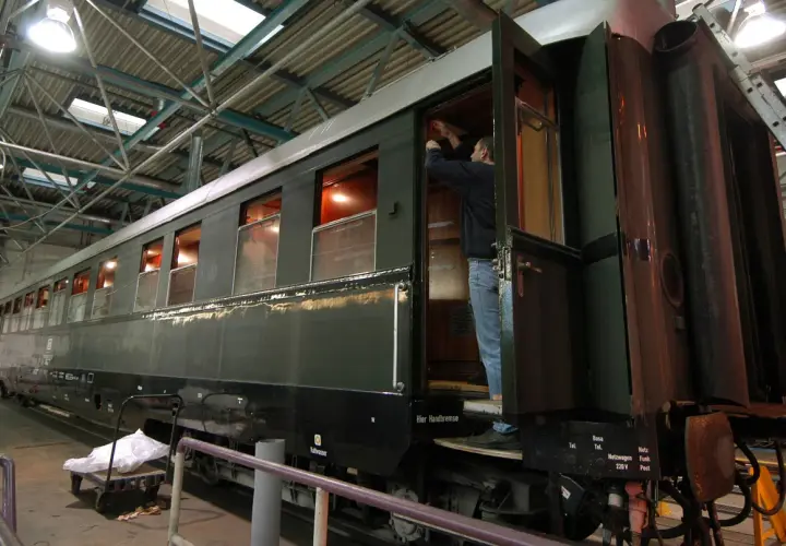 Ein Mann arbeitet an einem historischen Zugwaggon, der an Hitlers Panzerzug erinnert.