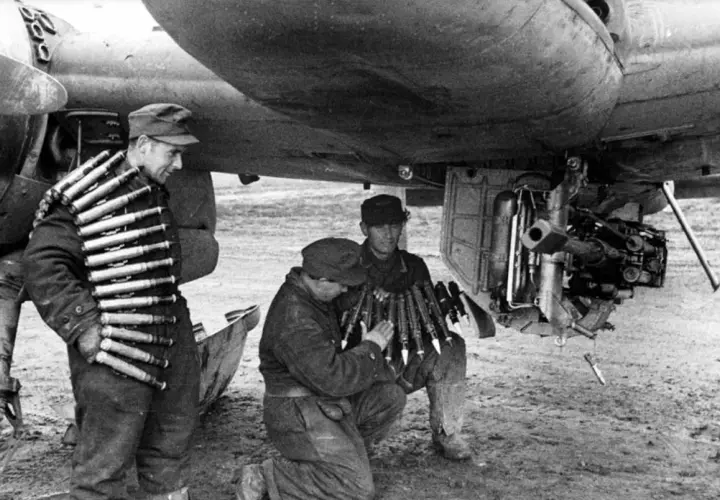 Soldaten laden Munition für ein Flugzeug. Ein Mann trägt Patronengurte, die mk 103 sind bereit.