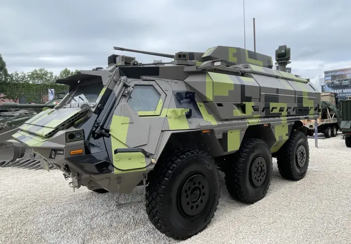 Ein gepanzertes Fahrzeug mit Tarnmuster, das als Fennek-Nachfolger präsentiert wird. Es verfügt über eine Waffenstation und mehrere Sensoren.