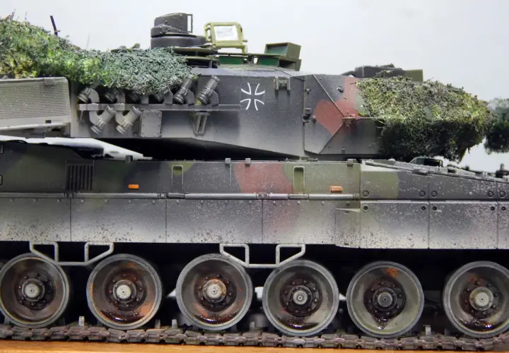 Detailaufnahme eines deutschen Panzers im Tarnmuster mit Tarnnetz. Das Modell zeigt die charakteristischen Räder und Ketten.