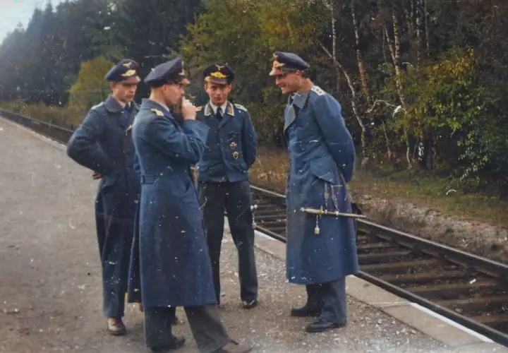 Vier Männer in blauen Uniformen, einige mit Portepee, stehen am Bahnsteig.
