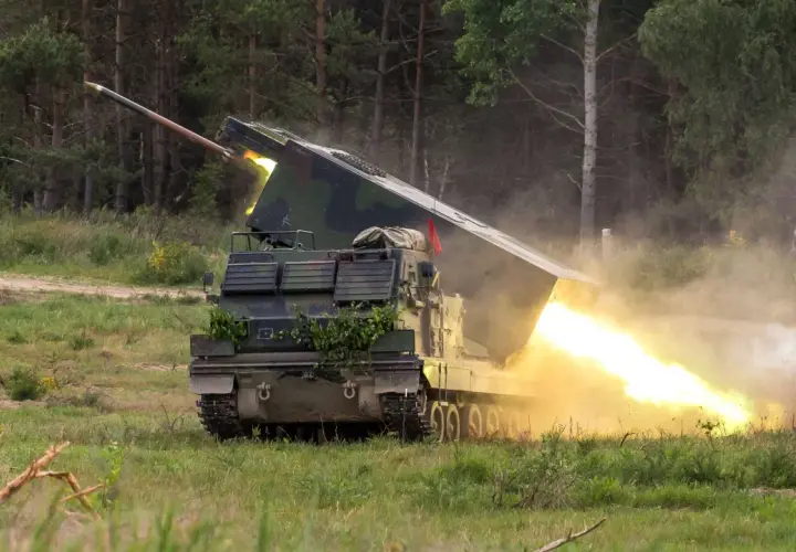 Ein Raketenwerfer auf Panzerbasis feuert eine Rakete ab, begleitet von hellem Feuer und Rauch.