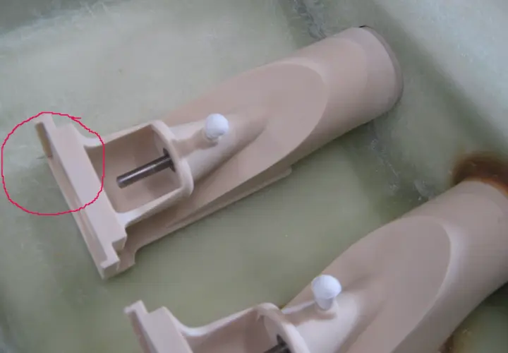 Zwei Teile eines wellenantrieb d-drive Systems, beige, mit Metallachsen und weißen Kugeln, liegen in einer grünen Flüssigkeit.