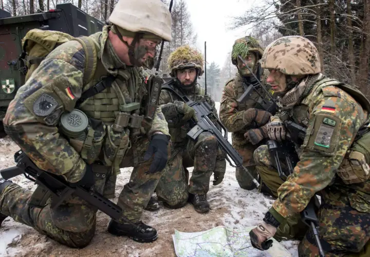 Soldaten der Bundeswehr im Wald, ein Leutnant deutet auf eine Karte.