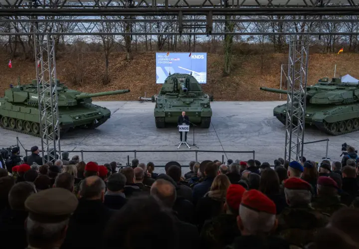Drei Panzer, ein Redner und eine Zuschauermenge bei einer Veranstaltung.