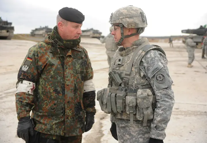 Zwei Soldaten im Gespräch, einer mit deutschem Tarnmuster und schwarzem Barett, der andere in US-Uniform. Der deutsche Soldat trägt den oberstleutnant dienstgrad.