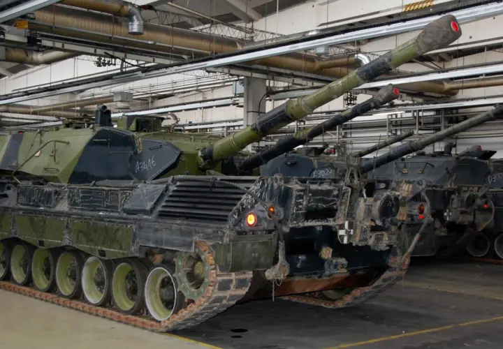 Mehrere Leopard 1 Panzer stehen in einer Halle. Ihre Kanonen ragen nach oben.
