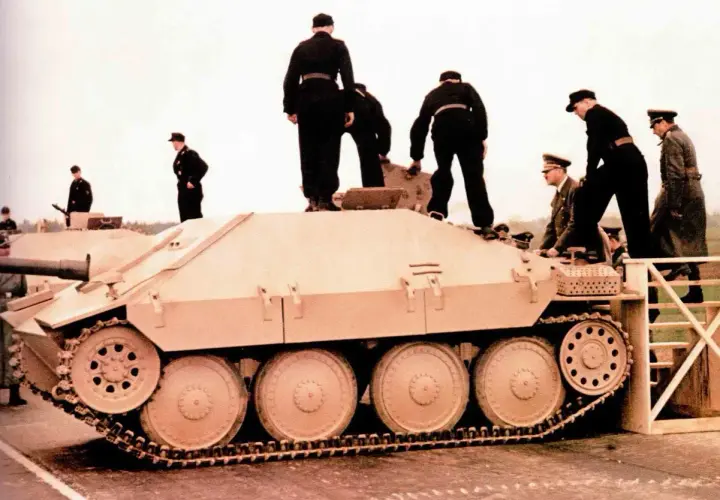 Männer in Uniformen stehen auf und neben einem hellbraunen Opel Hetzer Jagdpanzer.