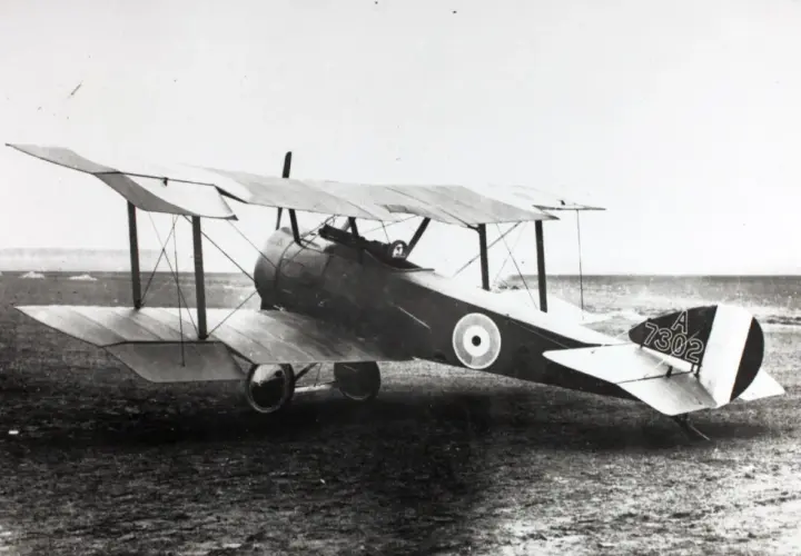 Ein Sopwith Pup Doppeldeckerflugzeug mit der Kennung A 7302 steht auf einem Feld.