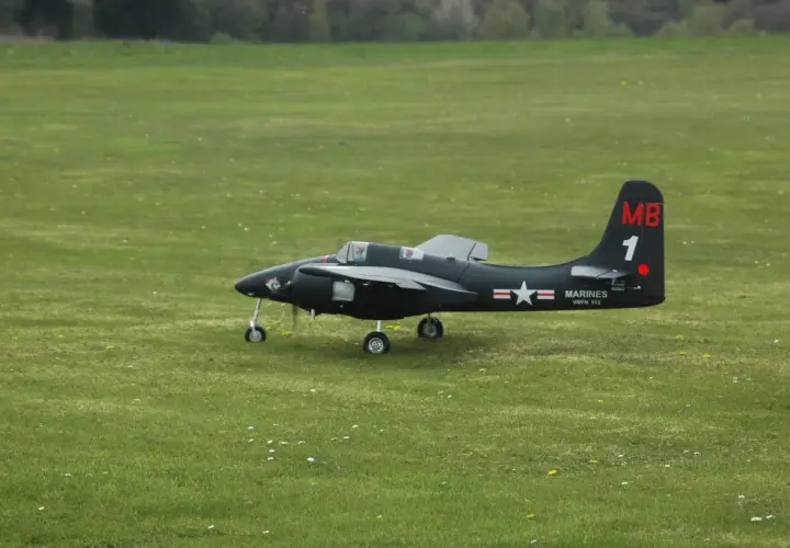 Ein schwarzes Modellflugzeug, ein f7f Tigercat, steht auf einem grünen Feld.