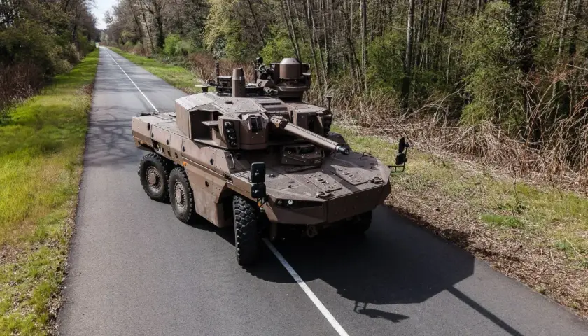 Ein moderner Jaguar-Panzer, ein stolzes Stück Militärtechnik aus Frankreich, fährt auf einer einsamen Straße durch bewaldetes Gebiet.