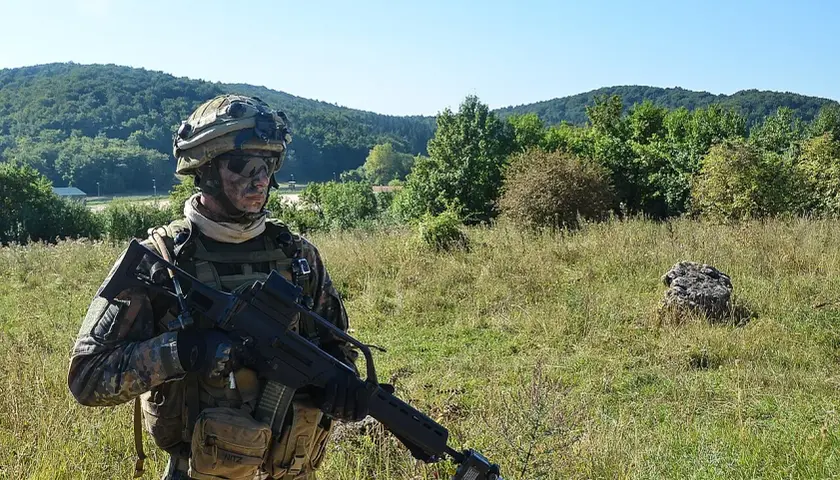 Soldat der Bundeswehr mit Tarnmuster und Gewehr im Feld. Die 5 Streifen auf seiner Ausrüstung sind kaum zu erkennen.