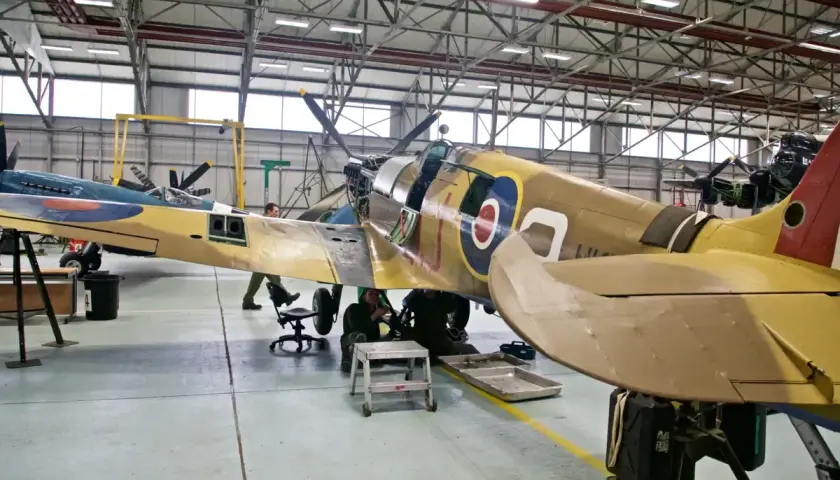 Flugzeugmuseum Usedom: Techniker arbeiten an einem historischen Jagdflugzeug in einer Werkstatthalle.