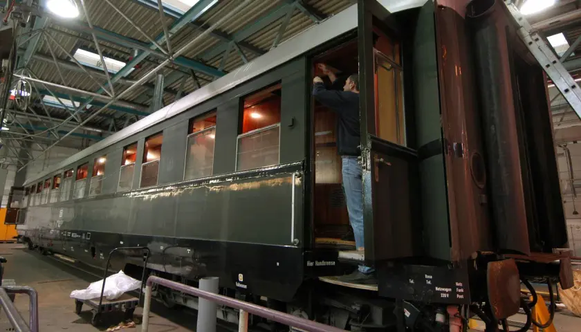 Ein Mann arbeitet an einem historischen Zugwaggon, der an Hitlers Panzerzug erinnert.